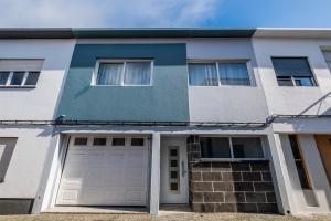 a white and blue house with a garage at Casa da Nau in Ponta Delgada