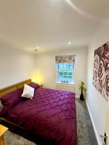 a bedroom with a purple bed and a window at The Gorge Getaway - Deluxe 3-Bedroom Apartment in Cheddar