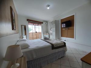 a bedroom with a large bed and a window at Pousada Magia do Sol in Florianópolis