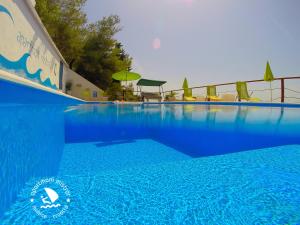 a large blue swimming pool with chairs and an umbrella at Apartments Mistral in Mimice