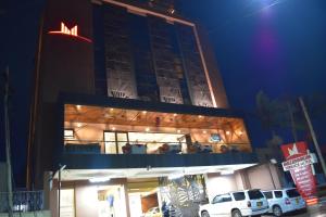 un edificio con dos coches blancos estacionados frente a él en Millennium Terrace Hotel en Kampala