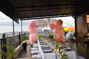 een lange tafel met ballonnen en borden met voedsel bij Millennium Terrace Hotel in Kampala
