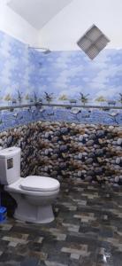 a bathroom with a toilet in front of a stone wall at top sea view guest in Mirissa