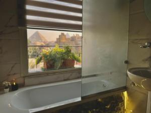 La salle de bains est pourvue d'une baignoire et d'une fenêtre avec une plante. dans l'établissement The Museum Boutique, au Caire