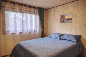 Schlafzimmer mit einem Bett und einem Fenster in der Unterkunft Cabaña Los Mañios in Puerto Montt