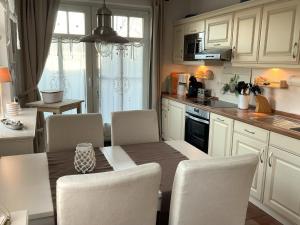 a kitchen with a table and chairs and a kitchen with white cabinets at Deichhof Whg 23 in Dunsum
