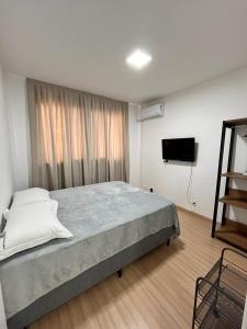 1 dormitorio con 1 cama grande y TV en LOCALIZAÇÃO PERFEITA! Ap Beira Mar, en Balneário Camboriú