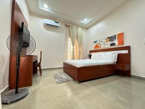 a bedroom with a bed and a desk and a fan at Ashers Villa in Abuja