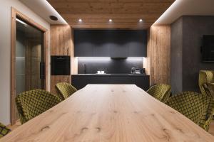 DOLOMITI EXCLUSIVE YOUR MOUNTAIN SUITE في بوتسا دي فاسّا: قاعة اجتماعات مع طاولة وكراسي خشبية