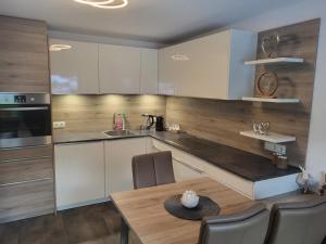a kitchen with white cabinets and a wooden table at Apart Bergluft in Pfunds