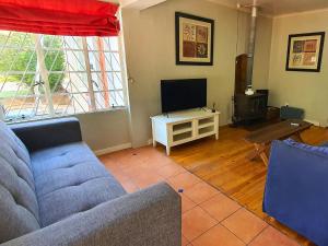 a living room with a couch and a tv at The Browns' - Cottage Suites in Dullstroom