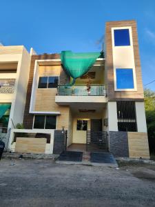 a building with a balcony with a green umbrella on it at Holiday Home in Ujjain