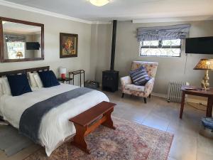 um quarto com uma cama grande e uma cadeira em The Browns' - Cottage Suites em Dullstroom
