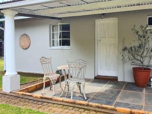 two chairs and a table in front of a house at The Browns' - Cottage Suites in Dullstroom