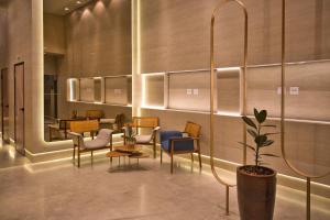 a lobby with chairs and tables and a potted plant at Life Residence in Belo Horizonte +35 photos