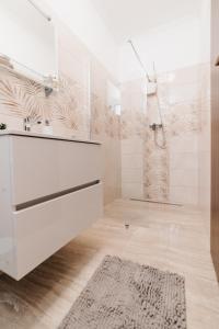 y baño con ducha, tocador blanco y cabina de ducha acristalada. en Oliver Apartman, en Makó