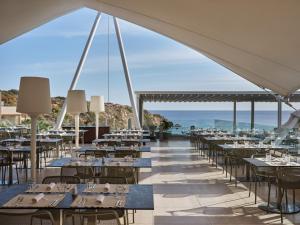 Atlantica Mikri Poli Crete في ماكري جيالوس: مطعم به طاولات وكراسي مع المحيط في الخلفية
