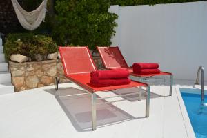 2 sillas rojas sentadas junto a una piscina en Villa Sitges Altavista Amazing View South oriented Calm Area AC Beach 2 minutes, en Sitges