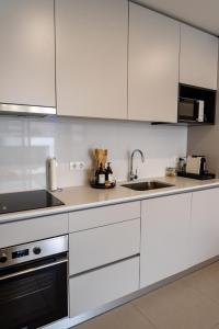 una cocina con armarios blancos y fregadero en Modern apartment with balcony and free parking en Oporto