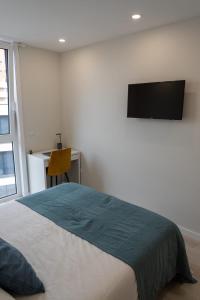 a bedroom with a bed and a tv on the wall at Modern apartment with balcony and free parking in Porto