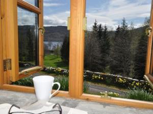 a coffee cup sitting on a table in front of a window at 1 Bed in Loch Ness I662C in Invermoriston