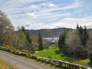 a road next to a field of flowers and a lake at 1 Bed in Loch Ness I662C in Invermoriston