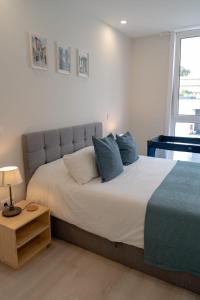 1 dormitorio con 1 cama blanca grande con almohadas azules en Modern apartment with balcony and free parking en Oporto