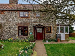 a stone house with a red door and flowers at 2 bed in Stanhoe POCN8 in Stanhoe