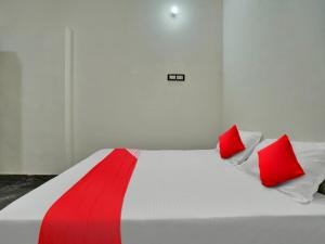 Una cama blanca con dos almohadas rojas. en OYO Home Hotel White Town en Bhilai
