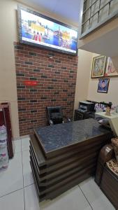 a waiting room with a tv on a brick wall at Kesari root in Amritsar
