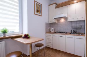uma cozinha com armários brancos e uma mesa de madeira em Modern Apartment at Classic Warsaw. Free parking. em Varsóvia