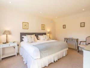 um quarto com uma grande cama branca e uma cadeira em 4 Bed in Dorchester 42204 em Frampton