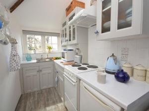 a kitchen with white cabinets and a stove top oven at 1 bed in Boscastle 42375 in Saint Gennys
