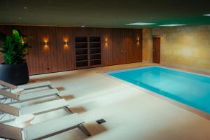 una piscina en una habitación con una silla y una mesa en Hotel Walram en Valkenburg