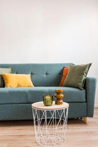 un sofá azul con almohadas y una mesa en la sala de estar. en AUTHENTIQUE, en Saint-Étienne