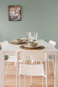 una mesa de comedor blanca con sillas blancas y una mesa con gafas en AUTHENTIQUE, en Saint-Étienne