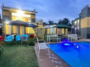 a swimming pool with chairs and tables and umbrellas at Platinum Guest lodge Germiston in Germiston