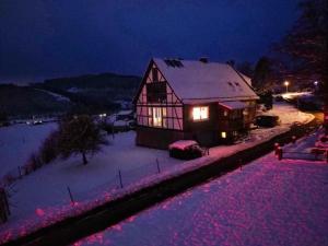 a house is covered in snow at night at Ferienwohnung am Denkmal in Bad Berleburg