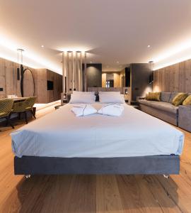 um quarto grande com uma cama grande e um sofá em DOLOMITI EXCLUSIVE YOUR MOUNTAIN SUITE em Pozza di Fassa