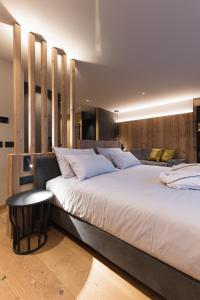 a bedroom with a large white bed with a table at DOLOMITI EXCLUSIVE YOUR MOUNTAIN SUITE in Pozza di Fassa