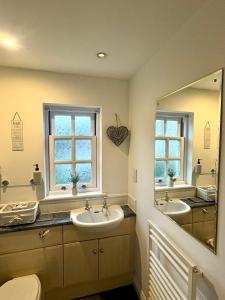 a bathroom with two sinks and a large mirror at The Gorge Getaway - Deluxe 3-Bedroom Apartment in Cheddar