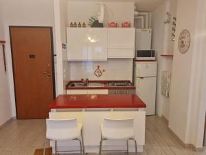 una cucina con piano di lavoro rosso e armadietti bianchi di Residenza Tartaruga a Lido Adriano