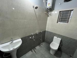 a bathroom with a white toilet and a sink at Urban Suites Silpukhuri in Guwahati