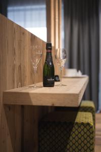 a bottle of wine and two wine glasses on a table at DOLOMITI EXCLUSIVE YOUR MOUNTAIN SUITE in Pozza di Fassa