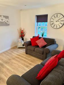 a living room with a couch and a clock on the wall at The Gorge Getaway - Deluxe 3-Bedroom Apartment in Cheddar
