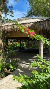einen Pavillon mit einem Grasdach mit Blumen darauf in der Unterkunft Jepun Villa 04 - One Bedroom without kitchen in Uluwatu