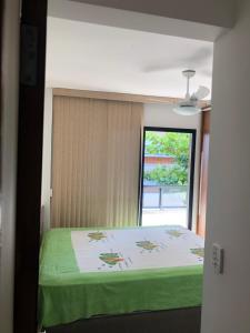 a bedroom with a green bed with a window at gaivotas com ar condicionado in Guarapari