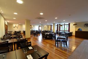 a restaurant with wooden floors and tables and chairs at Vista Azul Apart Hotel - Vista Pinheiros in Pedra Azul