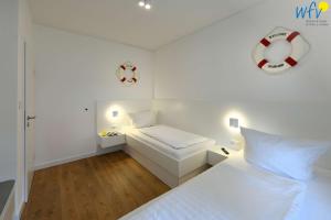ein weißes Schlafzimmer mit einem Bett und einem Strandball an der Wand in der Unterkunft Bungalow Hasela mit Workation Juist in Juist