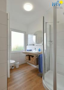 ein weißes Bad mit einer Dusche und einem Waschbecken in der Unterkunft Bungalow Hasela mit Workation Juist in Juist